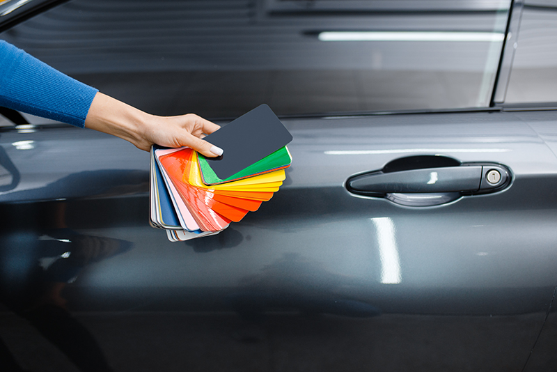 Car wrapping, male hand with protective vinyl foil or film color palette. Worker makes auto detailing. Automobile paint protection coating, professional tuning